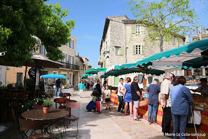 Scene of a Provençal market in La Colle-sur-Loup, in the heart of the village, perfect for showcasing local lifestyle and friendly atmosphere.