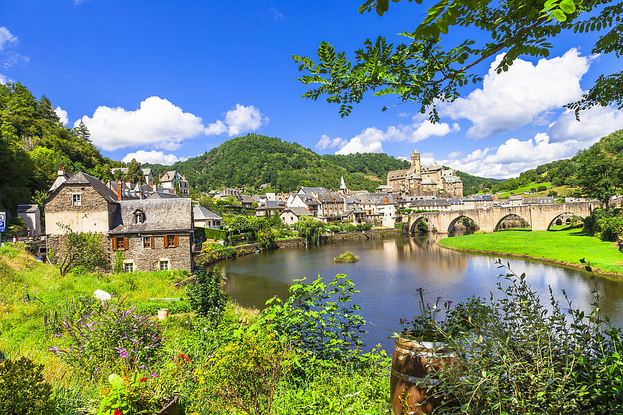 Picturesque view of a typical Périgord village with a stone bridge, peaceful river, and traditional houses, near a nature campsite in the Périgord region.
