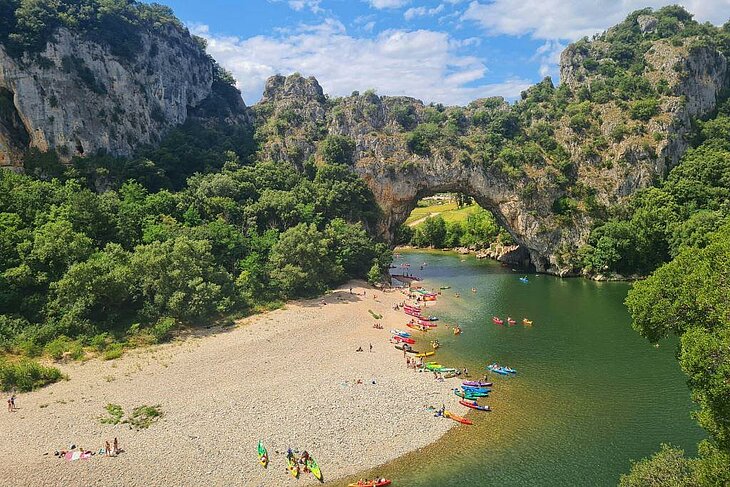 Colourful canoes on the river beneath the Pont d’Arc, a nature activity to enjoy around Joannas in Ardèche.