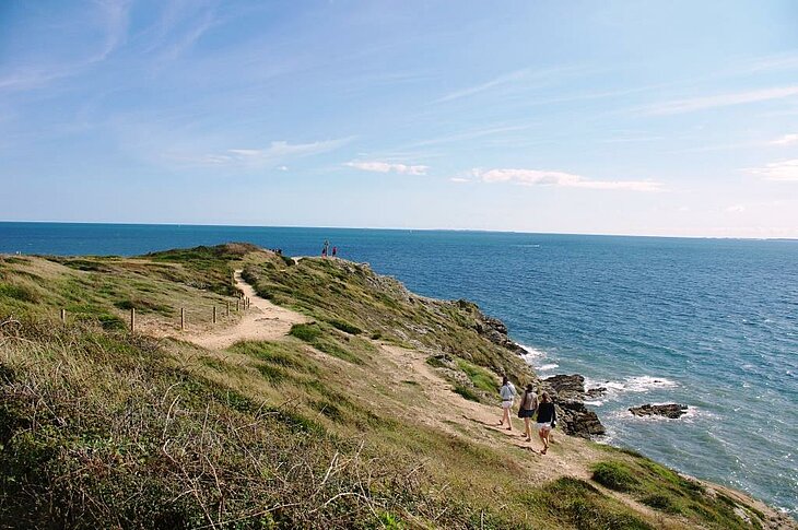 Coastal paths, must-do hikes in Morbihan Hikers on a coastal path in Morbihan, an ocean-view trail to explore when discovering what to do in Morbihan.