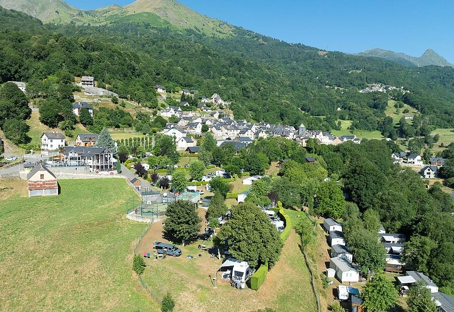 Aerial view of a campsite in the Pyrenees, near a traditional mountain village, surrounded by nature in southern France.