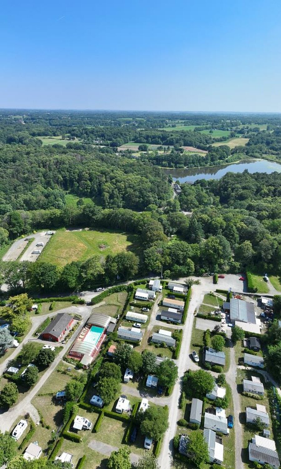 Aerial view of a 3-star campsite in France with mobile homes, pool and green nature, ideal for family holidays.
