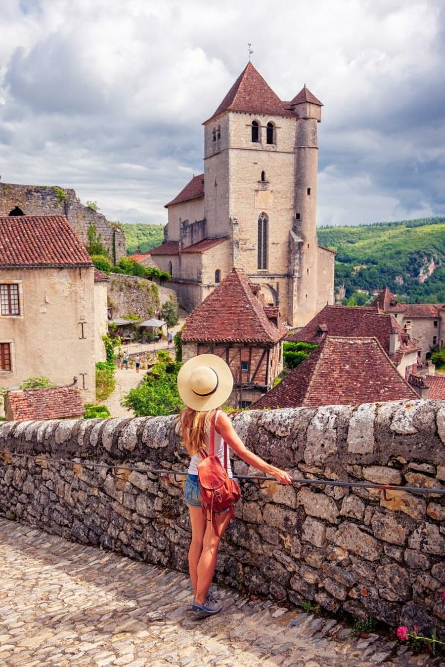 Traveller overlooking Saint-Cirq-Lapopie and its church in the Lot during a camping holiday in Occitanie.