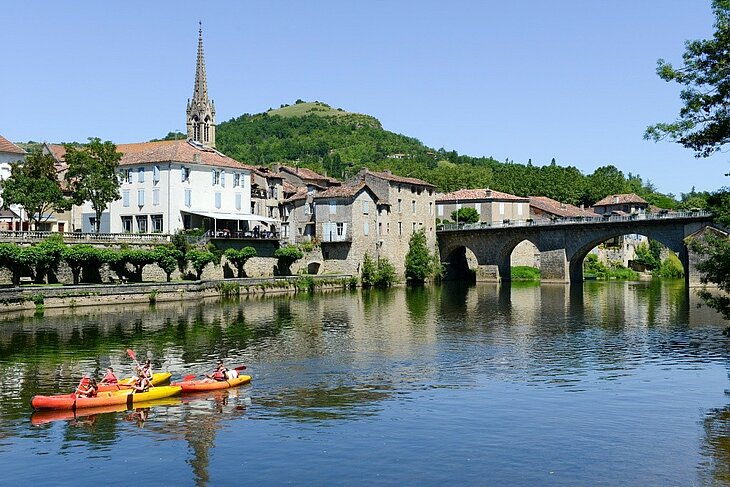 Canoeing on the Aveyron River in Saint-Antonin-Noble-Val Canoes on the Aveyron River, with the bridge and houses of Saint-Antonin-Noble-Val in the background, in the heart of the Aveyron Gorges.