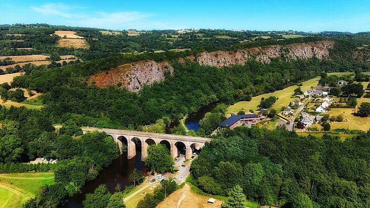Aerial view of Suisse Normande in Normandy, green valley, river and stone viaduct, a nature adventure for families.