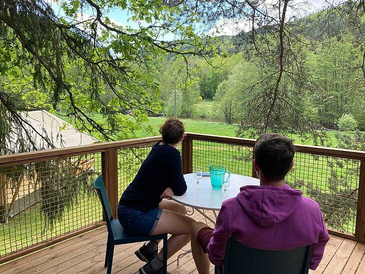 Couple relaxing on a terrace overlooking nature at a campsite, peaceful and intimate moment for a romantic getaway.