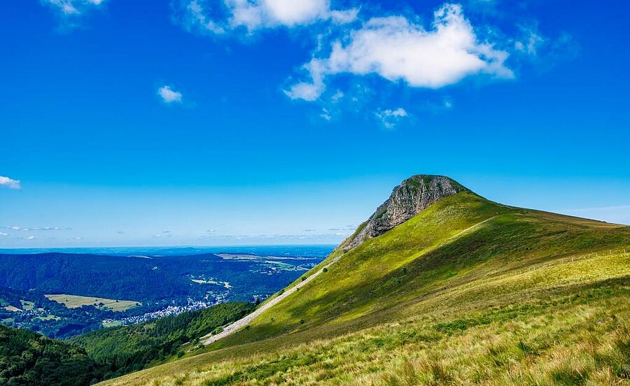 Volcanic landscape of Auvergne with a green summit and a wide, open view over the valley.