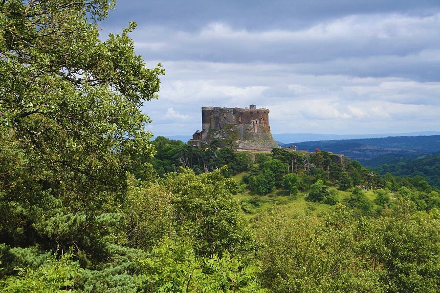 Aerial view of Murol Castle overlooking the valley, surrounded by forests and traditional Auvergne villages.