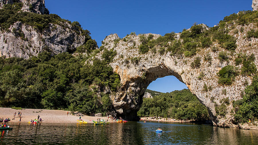 Canoes at the foot of the Pont d’Arc in Vallon Pont d’Arc, an iconic site of the Ardèche Gorges near nature campsites