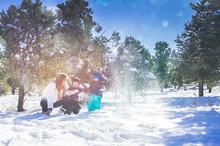Snow Games During Family Winter Holidays Family playing in the snow under the sun, laughter and bonding during the winter break.