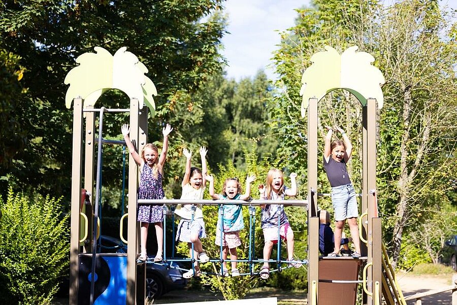Children playing on a playground in a natural setting within a campsite in Brittany, perfect for friendly and memorable family holidays.