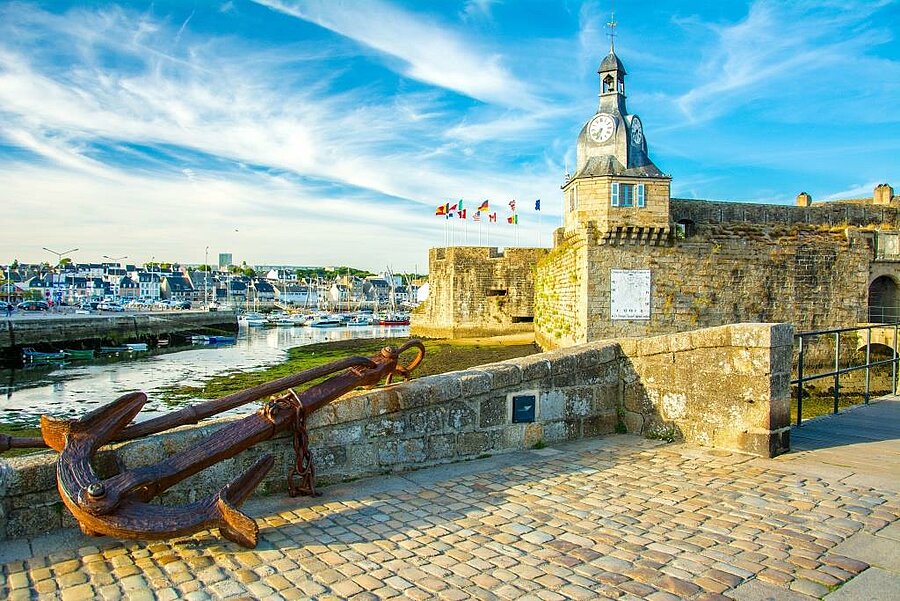 Anchor in the foreground facing the walled town and clock tower of Concarneau harbour, perfect for a camping Concarneau stay in Brittany.