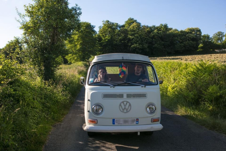 Couple driving a retro van on a small countryside road, showing the ease of early booking couple.