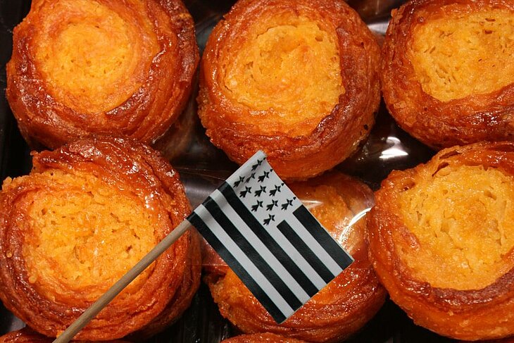 Kouign-amann, a Breton delight Golden Kouign-amann, a buttery Breton speciality with the Breton flag, a gourmet emblem of Finistère Tourism.