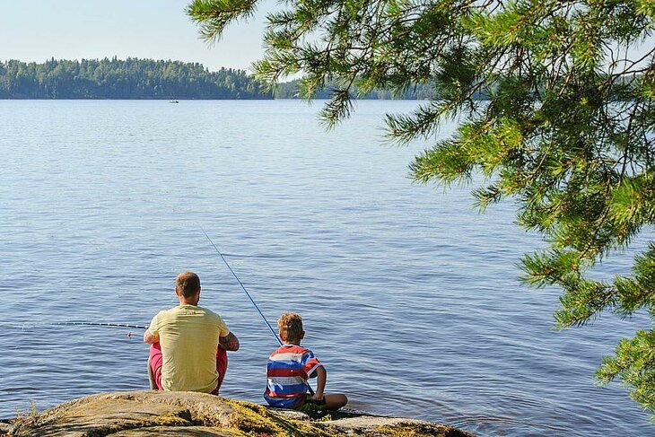Father and son fishing by a lake in the Vosges, an ideal outdoor activity to enjoy as a family.