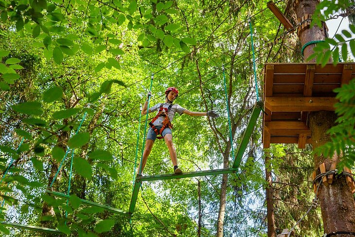 Girl on a treetop course in the heart of the forest at Oasis Aventura, a fun and active experience perfect for families staying around Eclassan.