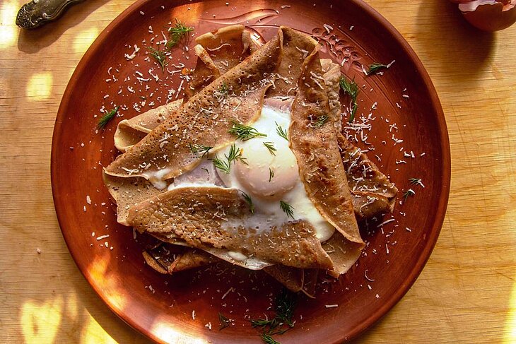 Filled Breton galette served on a plate, a local speciality to enjoy during a gourmet stay, a tasty idea when wondering what to do in Brittany.