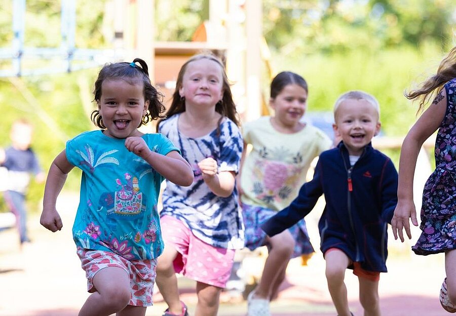 A group of children running and playing in a playground at a Sites et Paysages campsite—a joyful escape for the Ascension weekend.