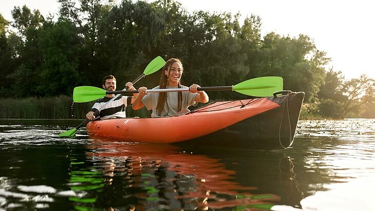 Two friends paddling a canoe on the Orne in Normandy at sunset, a friendly outdoor activity to share with friends.
