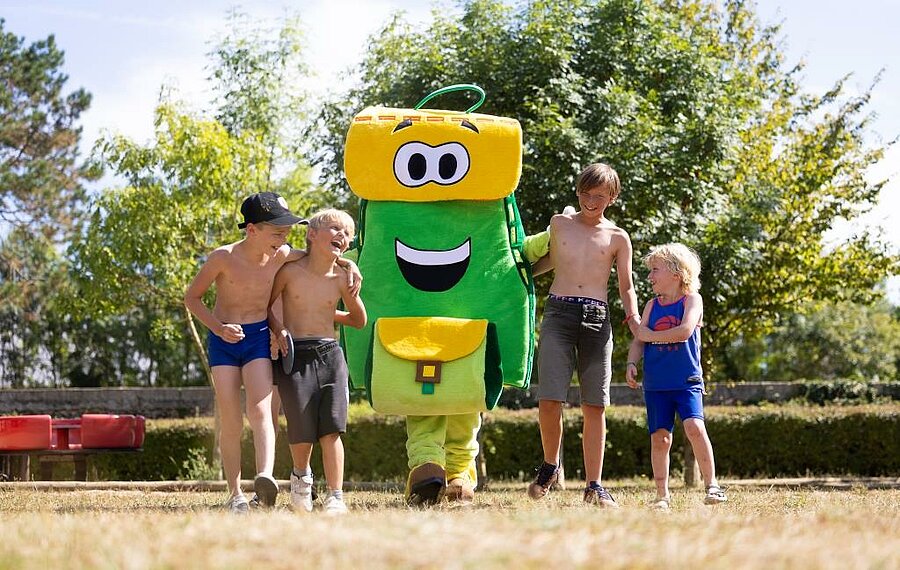 Children having fun with Pako, the mascot of Sites et Paysages campsites, in a lush green setting – perfect for a family holiday near the Loire Valley castles.