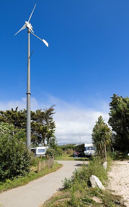 Wind turbine on a nature campsite, showing the collective commitment of Sites et Paysages to sustainable tourism and renewable energy