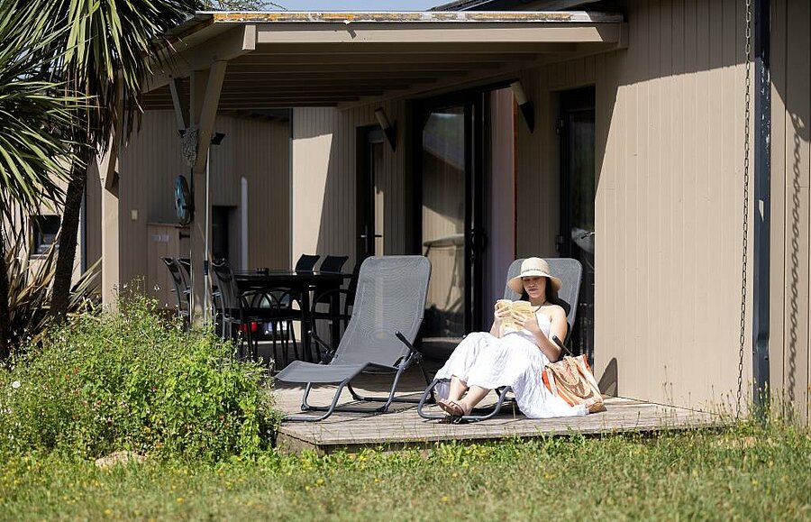 Holidaymaker relaxing on the terrace of a comfortable accommodation at a peaceful 4-star campsite.