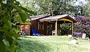 Wooden chalet in a campsite, surrounded by greenery, offering comfortable accommodation for a nature-filled holiday.
