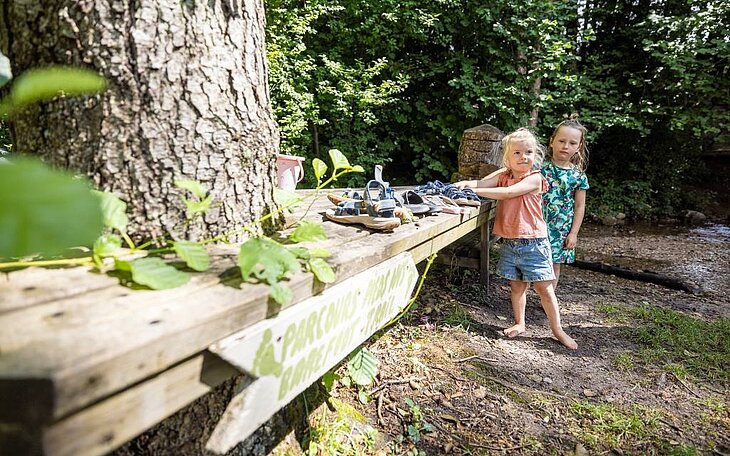 Two children exploring the barefoot trail at Au Clos de la Chaume campsite, a fun nature experience for Corcieux tourism in the Vosges.
