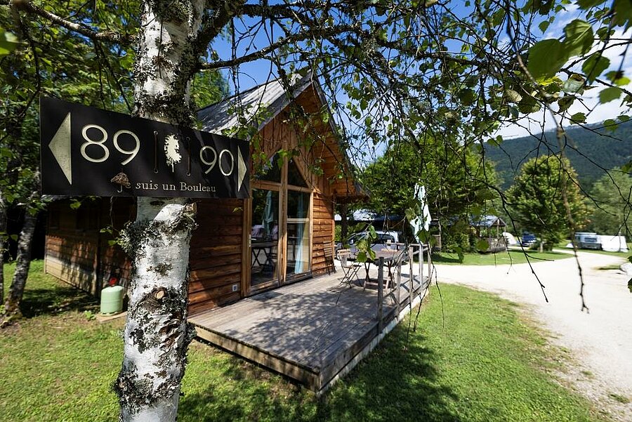 Wooden chalet nestled in greenery at a campsite, combining luxury, nature and authenticity for an exceptional stay.