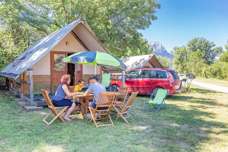 Family in front of a lodge tent in a campsite in the Hautes-Alpes, a nature rental ideal for an outdoor holiday