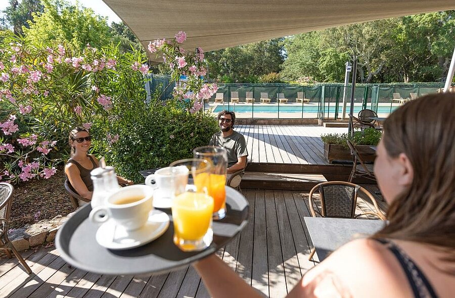 Drink service on a wooden terrace by the pool in a 3-star nature campsite in South Corsica
