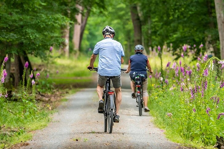 Cycling through a flowery forest path near Eclassan, an ideal nature activity to explore hamlets and historic buildings with the family.