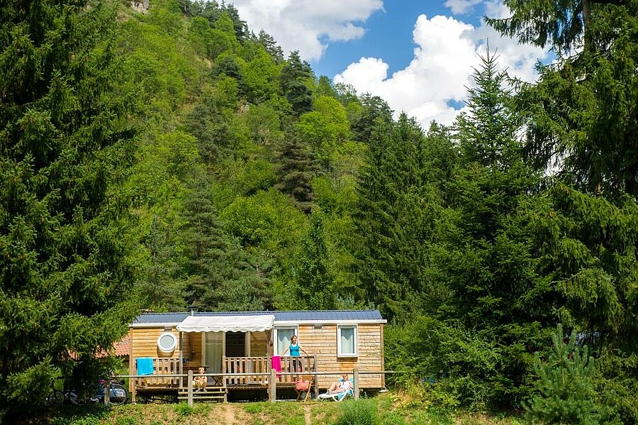 A wooden mobile home nestled in nature at a Sites et Paysages campsite, ideal for a relaxing stay during the Ascension weekend.