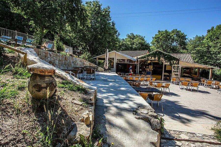 Shaded restaurant terrace in a campsite near Vallon Pont d’Arc, perfect for a friendly holiday in the heart of nature