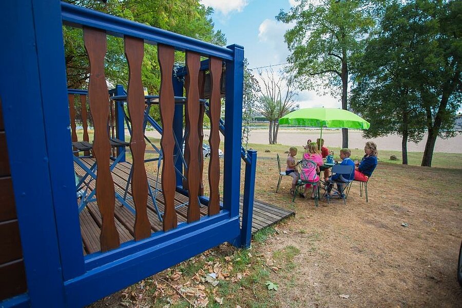Family enjoying breakfast outdoors in front of a colourful gypsy caravan at a campsite near the Sologne, with a view of the Loire.