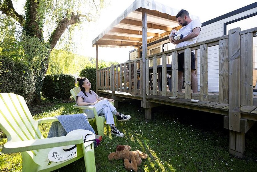 Family enjoying the terrace of a mobile home in a campsite near Le Havre, a comfortable and green accommodation in Normandy.