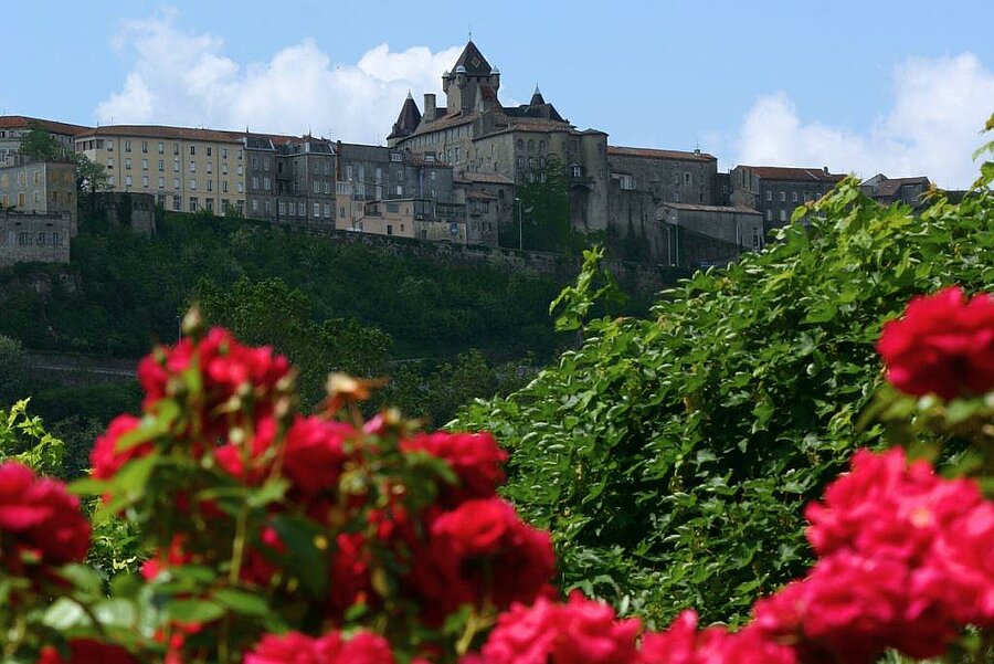 View of Aubenas Castle surrounded by greenery and flowers, a must-see destination for a campsite holiday in the region.