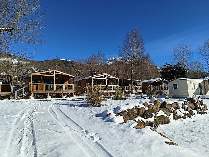 Wooden chalets at a snowy mountain campsite, peaceful setting for a cozy and romantic winter getaway.
