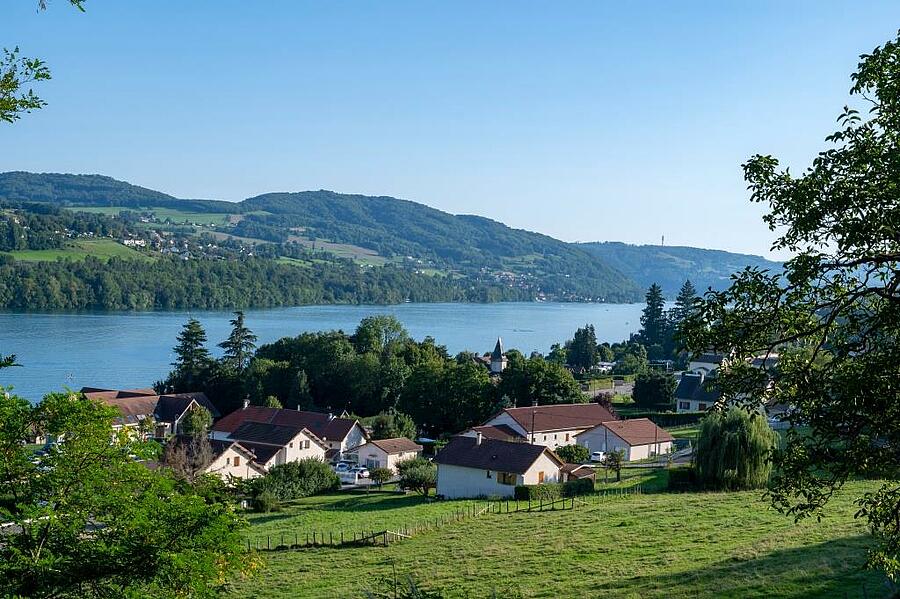 Panoramic view of Lake Paladru in Isère, surrounded by rolling green hills and charming villages — the perfect setting for a campsite holiday that blends nature with water-based activities.
