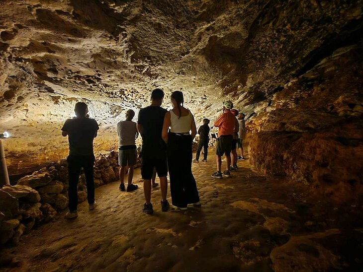 Visit to Bara-Bahau Cave Group of visitors exploring an illuminated rocky passage inside Bara-Bahau Cave in Le Bugue, Dordogne.
