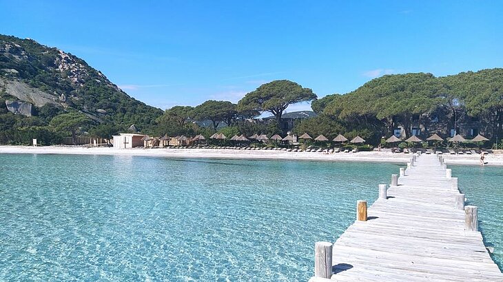 Santa Giulia Beach in South Corsica, shallow turquoise water, white sand and a wooden pier, perfect for swimming.