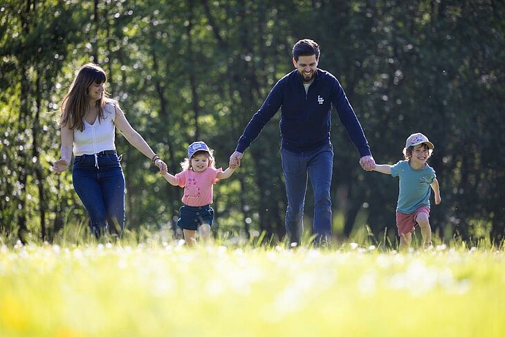 A family with children walking through a nature campsite, perfect for booking a friendly family holiday.