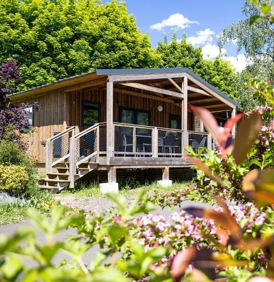 Wooden chalet surrounded by greenery at a campsite near Besse-et-Saint-Anastaise, comfortable rental for a family nature stay.
