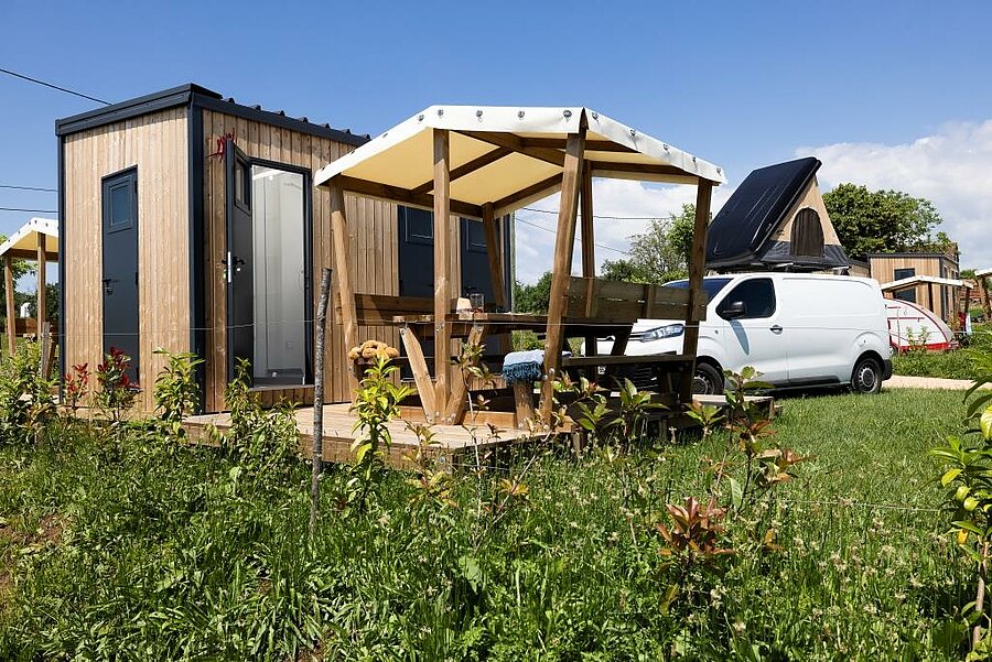 All-comfort van pitch with private facilities, garden furniture and fitted van, on a nature campsite in France.