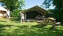 Spacious glamping tent with a terrace, set in a green environment, perfect for a family holiday combining comfort and nature.