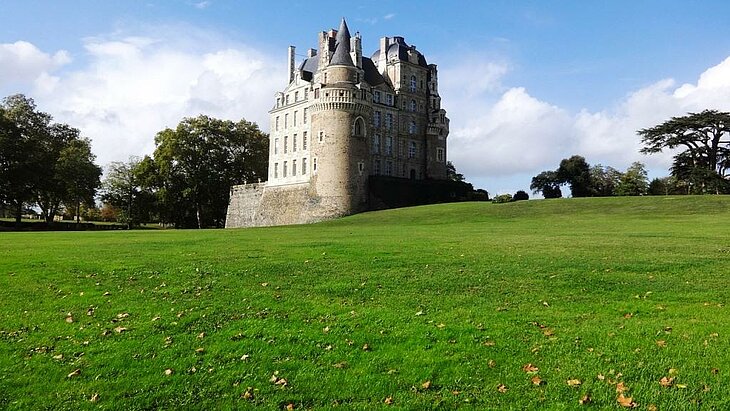 Brissac Castle, a jewel of Brissac Loire Aubance's historical and cultural heritage, nestled in greenery beneath a clear sky.