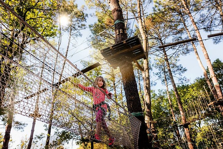 Family Treetop Adventure Course Child navigating a treetop adventure course in the forest, a popular family activity in the heart of tourism in Nouvelle-Aquitaine.