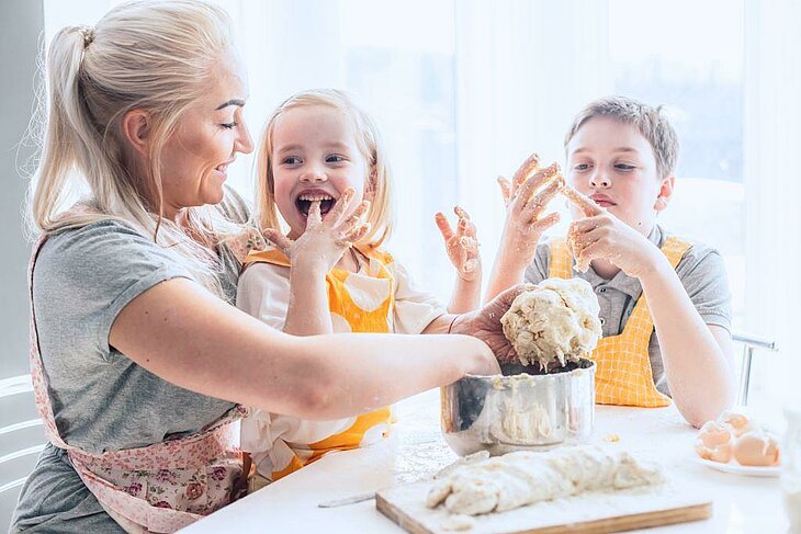 Cooking Workshop During Family Holidays Mother and children prepare cake batter at home, a fun and tasty hands-on activity.