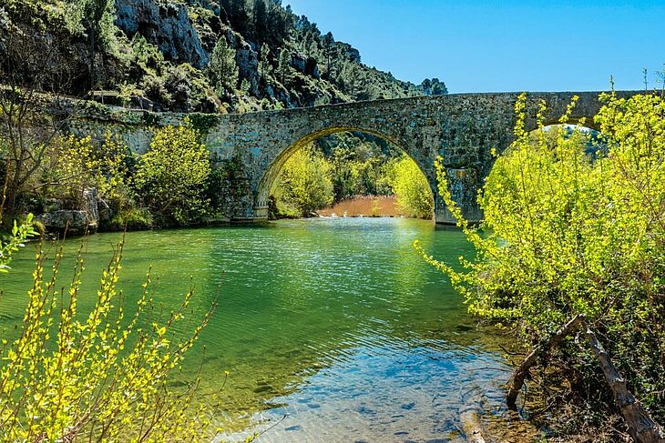 Stone bridge crossing the turquoise waters of the Orbieu Gorges, an ideal spot for outdoor activities during a tourism stay in Lézignan-Corbières.