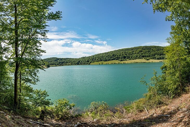 Panorama of Lake Ilay, surrounded by forests and green hills, a must-do walk around Mesnois.
